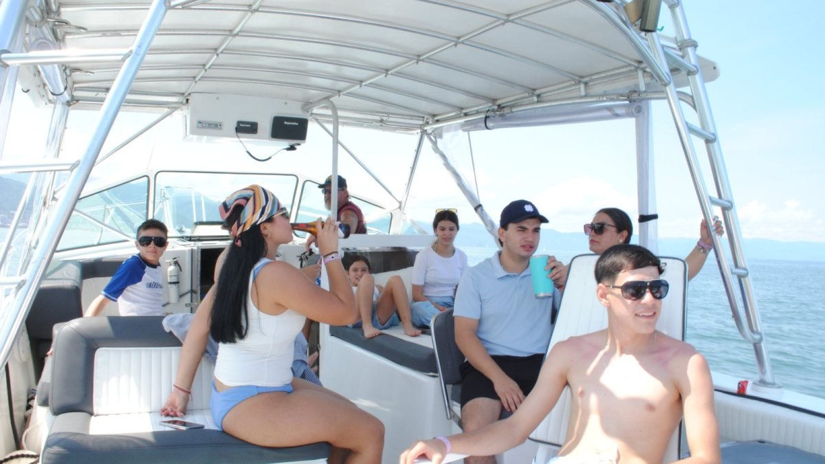 A family group cruising Banderas Bay under the shade canopy on a private boat charter from Nuevo Vallarta