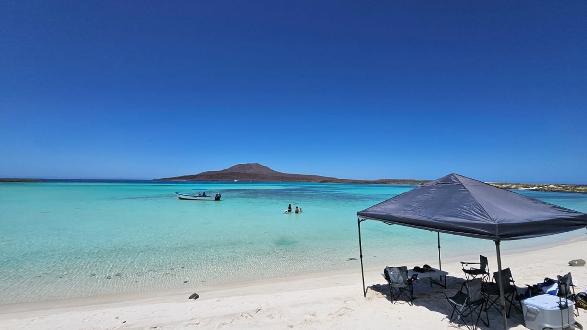 Shade tent, chairs and cooler set up on the white-sand beach of Isla Coronado during a Loreto island tour