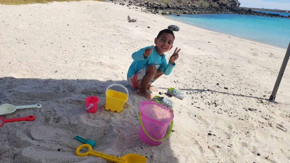 Child building sandcastles on the white sand beach of Isla Coronado during a private boat tour in Loreto