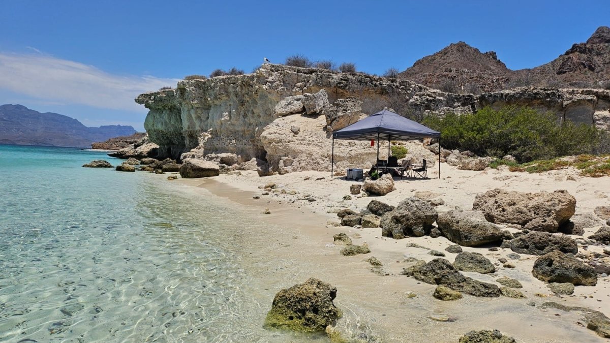 Shade tent and beach camp set up in a clear cove of Isla Danzante on a Loreto island tour