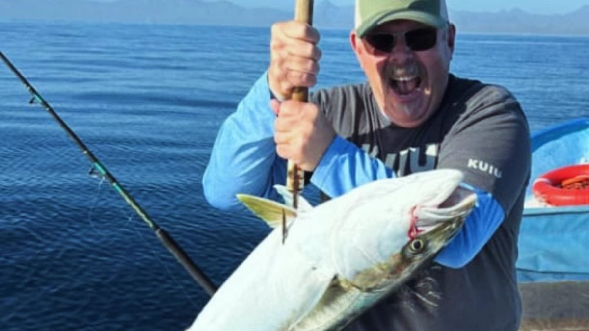 Laughing angler lifting a yellowtail on the rod during a winter fishing charter in Loreto, Sea of Cortez