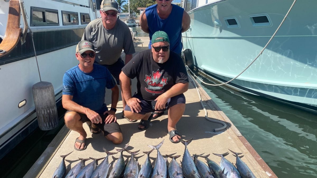 Charter group crouched on the dock at Marina Nuevo Vallarta behind a row of tuna from their fishing charter