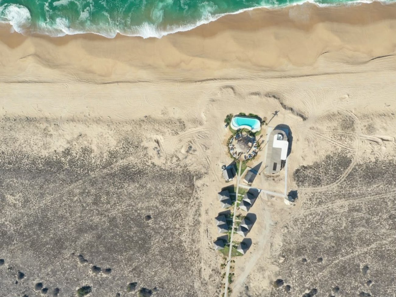 Aerial view of the Mayto hotel: palapa-roofed suites and a pool at the edge of the Costalegre beach