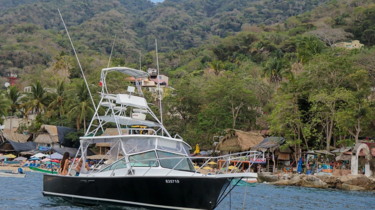 Private boat charter from Nuevo Vallarta anchored off a palapa-lined south-shore beach village in Banderas Bay