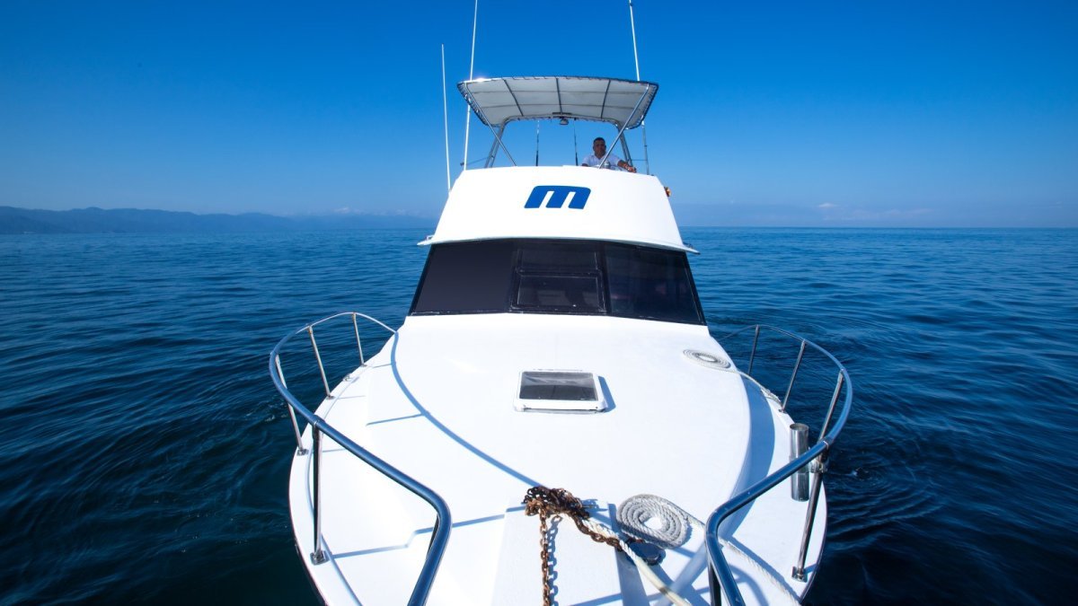 Bow of a private boat heading out across calm Banderas Bay on a flat-day yacht charter during a Puerto Vallarta surf trip