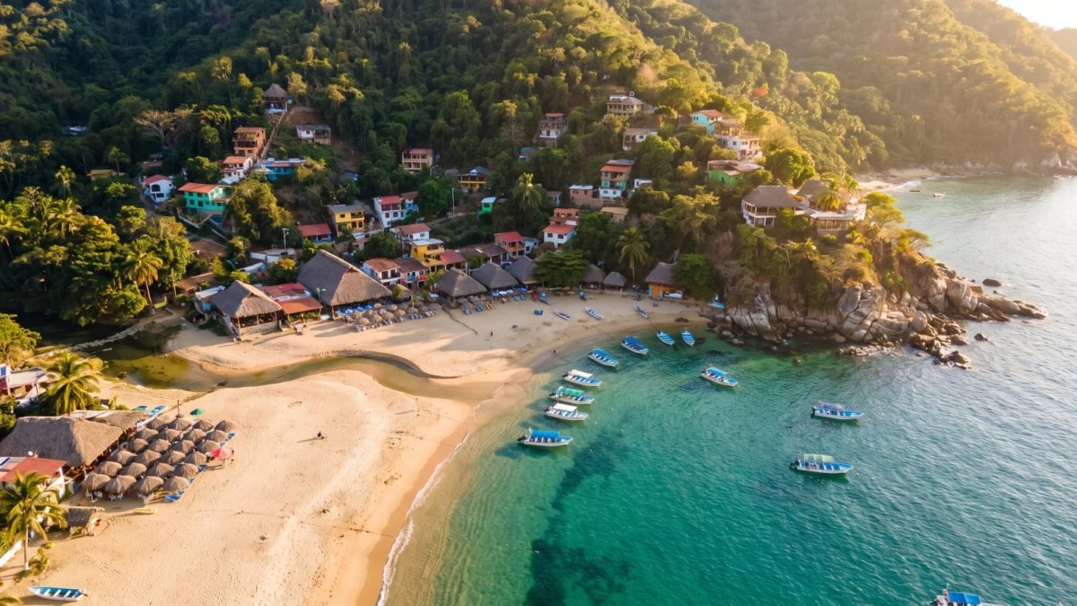 Yelapa village on a jungle hillside above its beach and river mouth, reached by private boat charter from Nuevo Vallarta